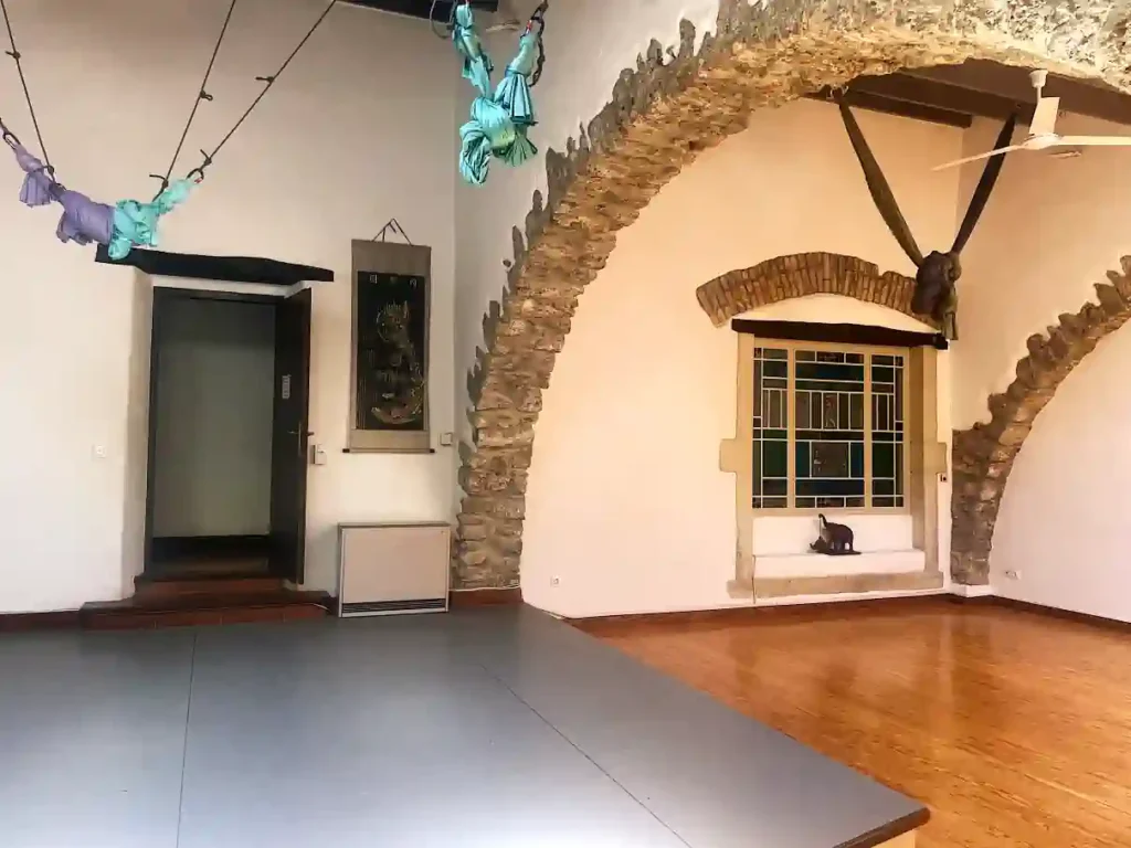 Casa Lucia Estia interior hall in Corfu with stone arches, wooden floor and aerial acrobatics equipment, featured by Corfu Vibes.